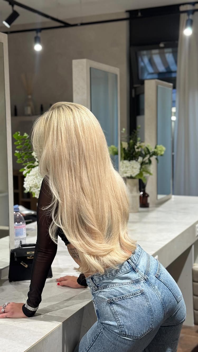 Long creamy beige-blonde hair with softly curled ends in a salon