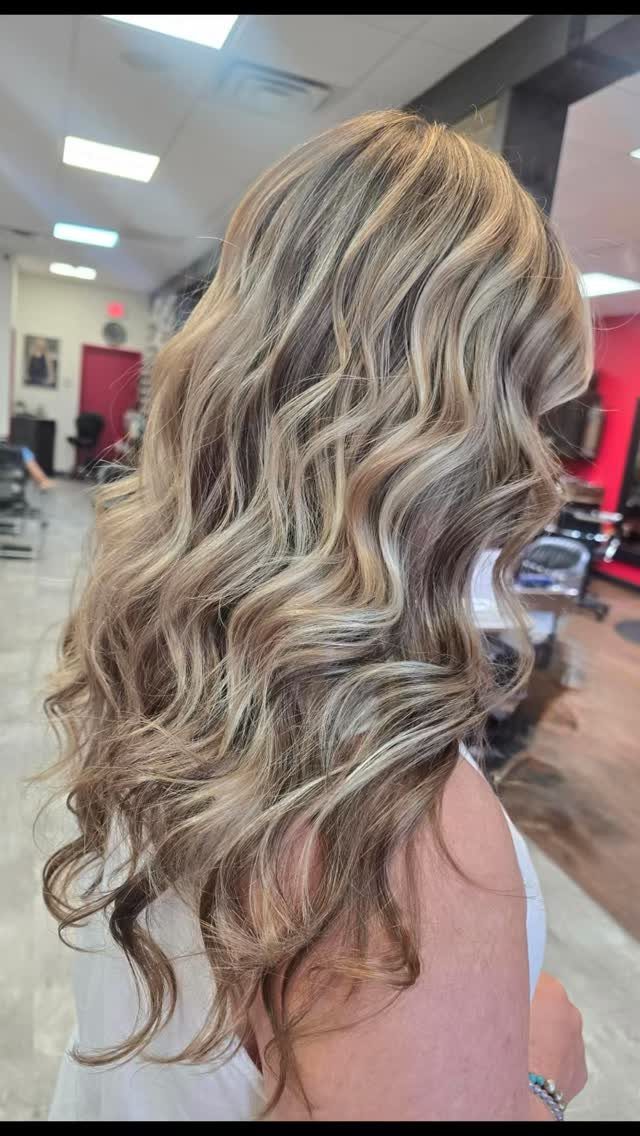 Wavy ash-blonde hair transitions from darker roots to lighter ends