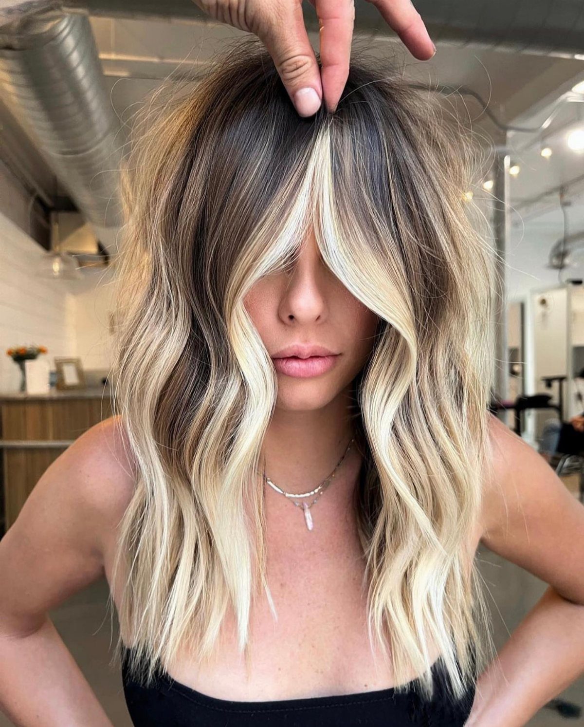 Dark-rooted blonde hair parted at the crown in a salon
