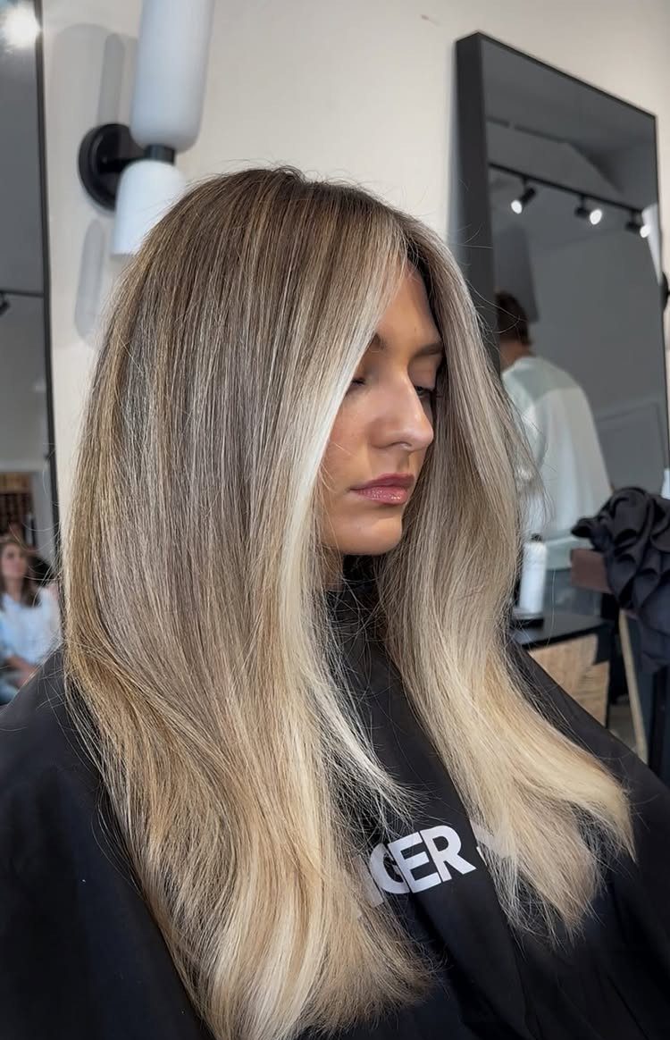 Woman with long, dark-rooted hair blending into beige blonde lengths