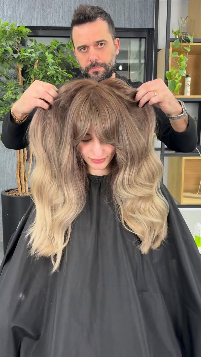 Wavy brunette-to-blonde ombre hair displayed by a hairstylist in a salon