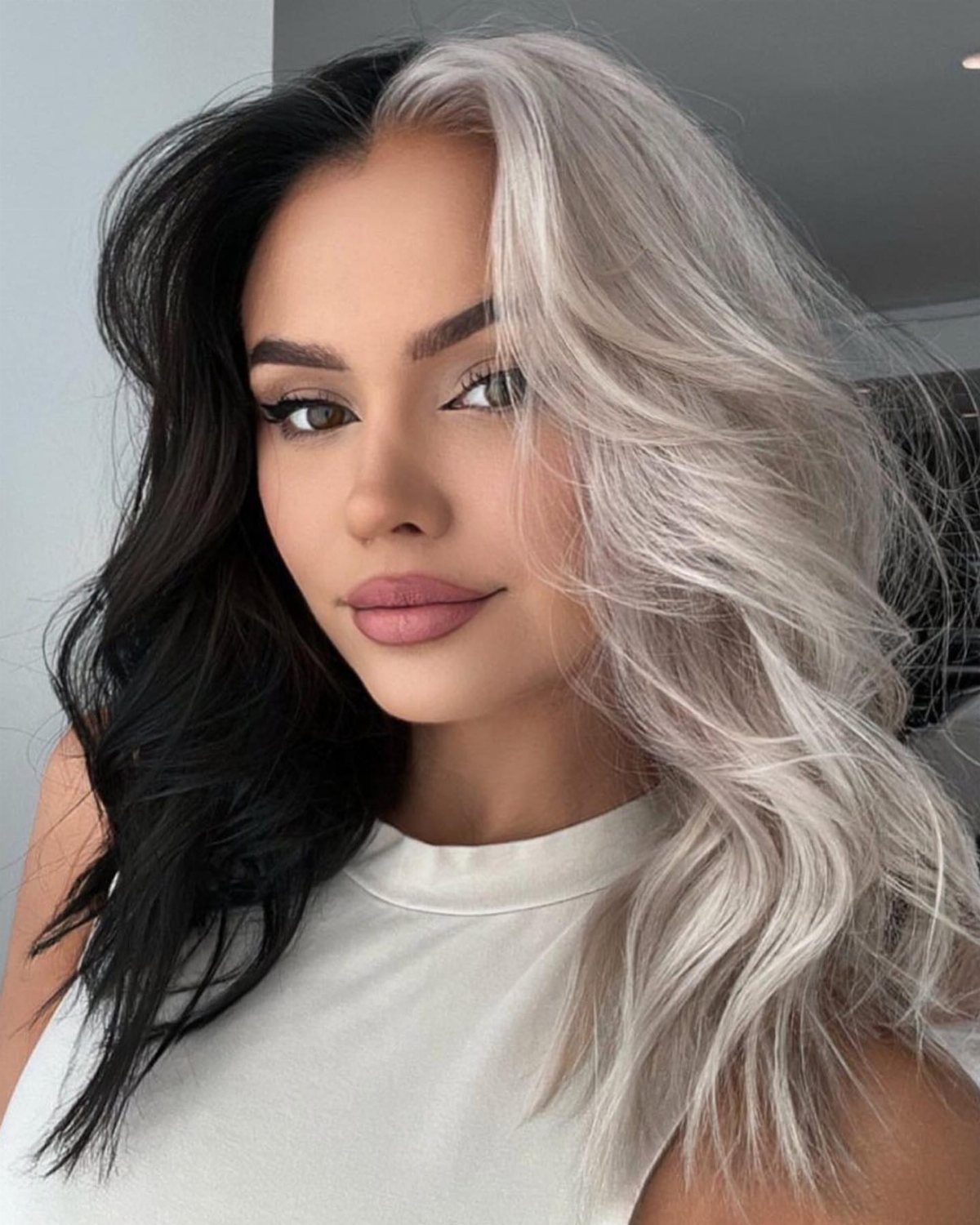 Woman with long wavy hair split between black and silver-gray
