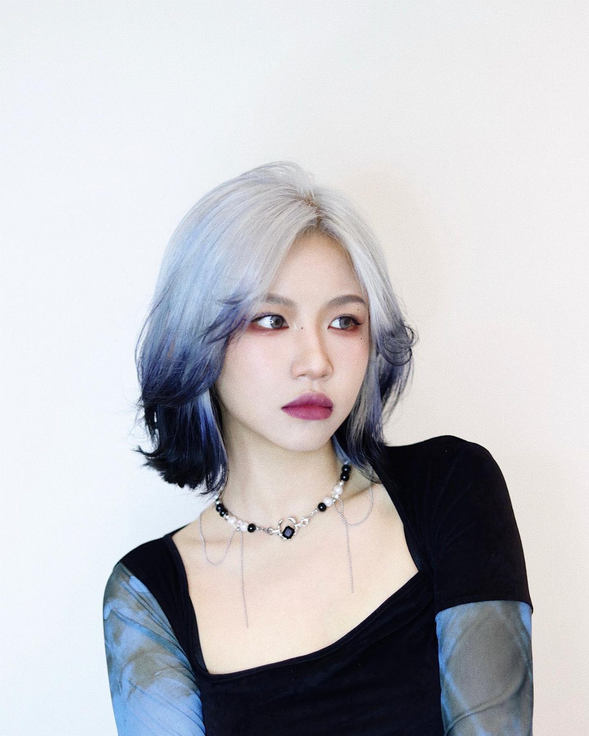 Woman with a layered silver-blue bob and dark navy hair ends