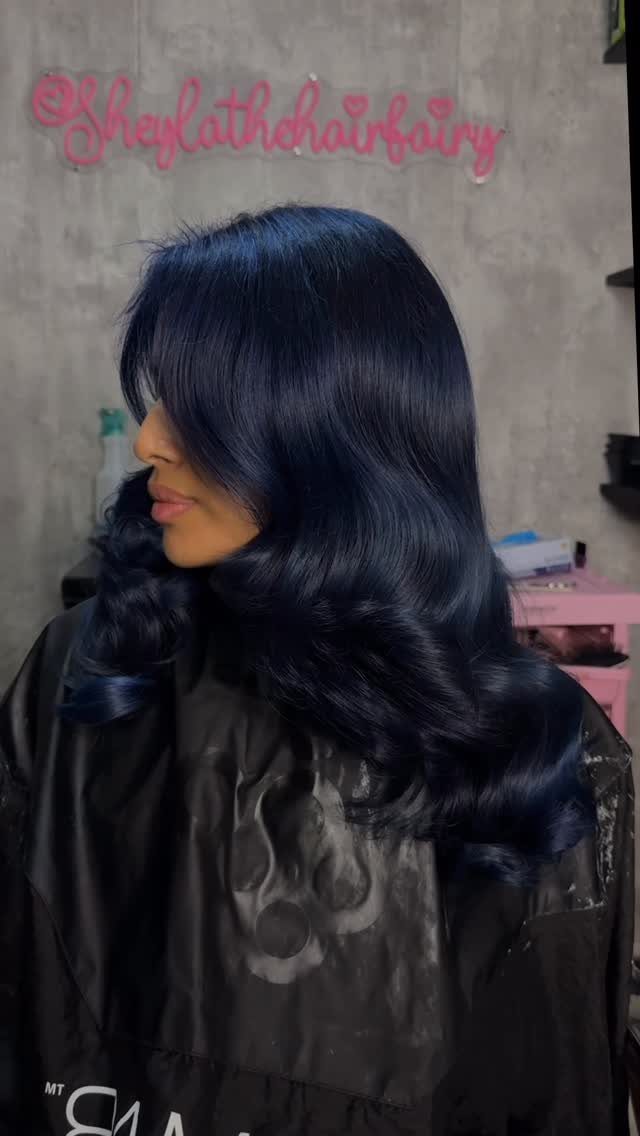 Woman with long, glossy midnight blue-black hair in a salon cape