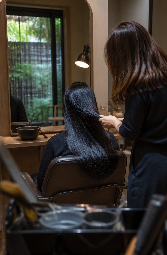 Sleek black hair with navy reflections beside a salon mirror