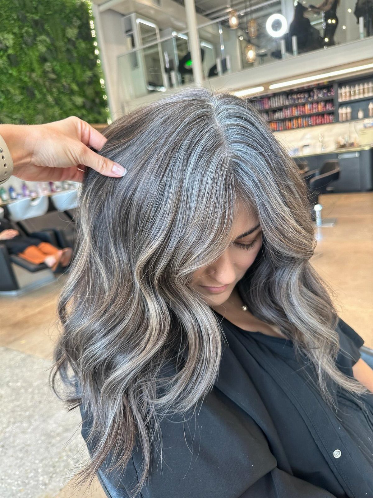 Woman with glossy silver-gray waves and darker lowlights in a salon