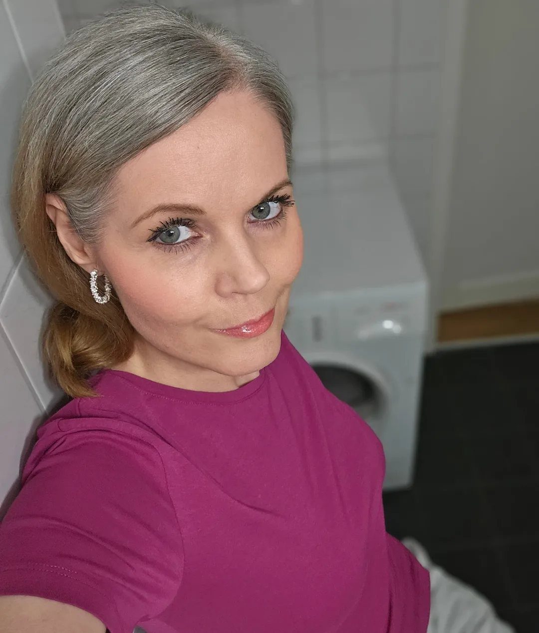 Woman with side-parted silver-gray hair wearing a magenta top