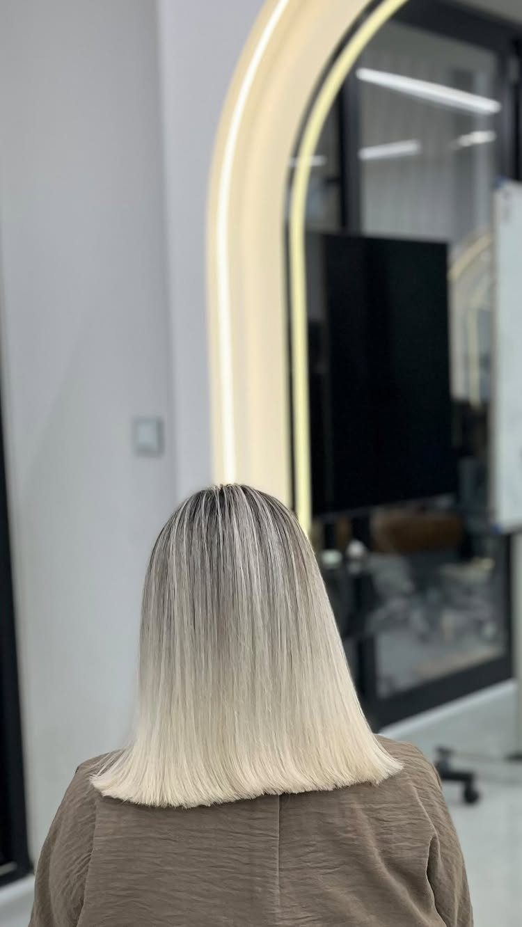 Straight silver-blonde hair fades from dark roots to pale, icy ends