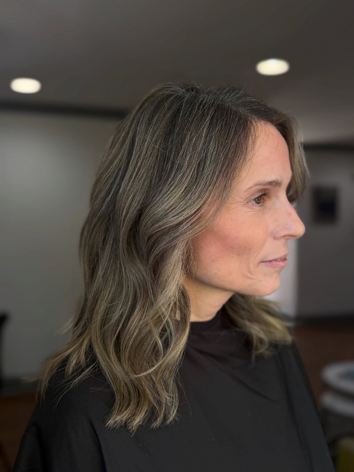 Woman with wavy mousy-brown hair blended with pewter-gray strands