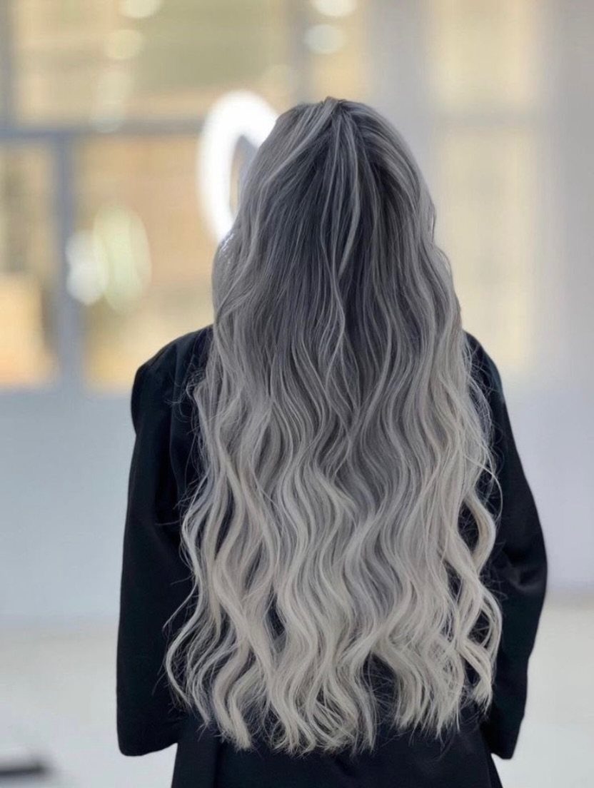 Long wavy hair fades from dark roots to icy silver-blonde ends.