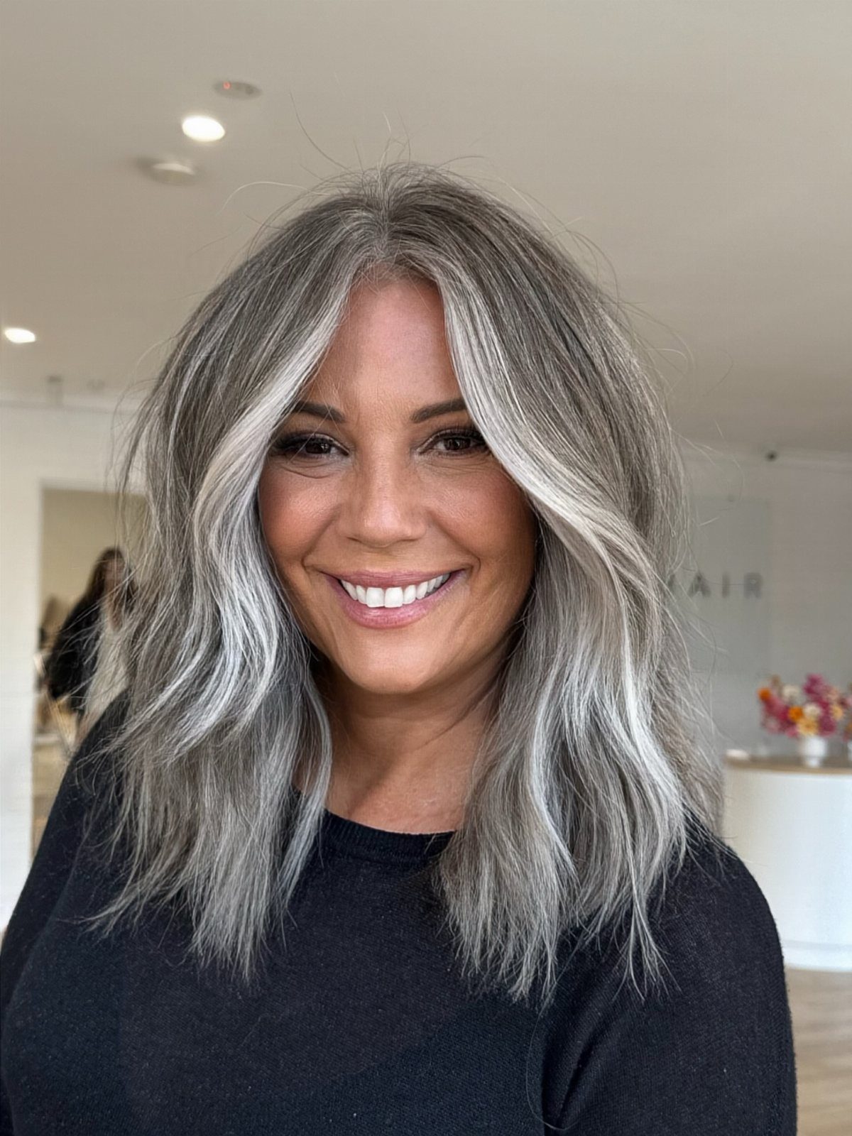 Woman with gray hair and silver-white face-framing highlights in a salon