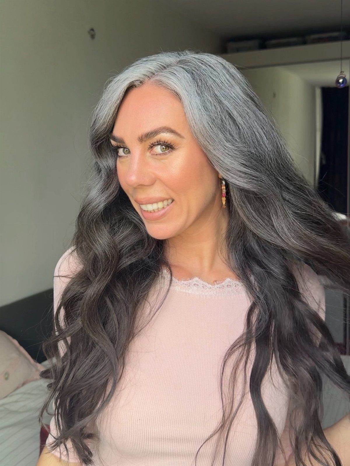 Woman with long dark waves and bold silver-gray face-framing sections