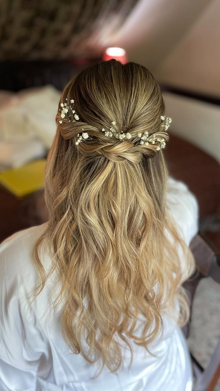 Blonde half-up curls decorated with a delicate band of tiny white flowers