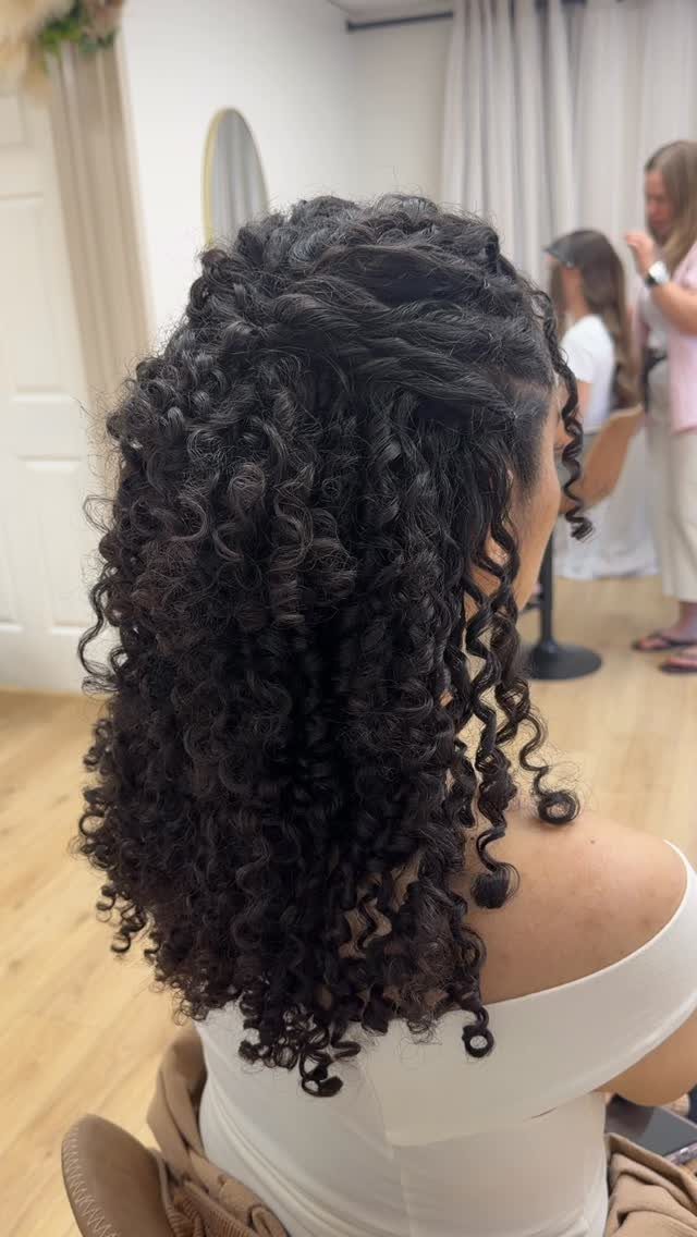 Dark curly hair pulled back at the crown and left cascading down