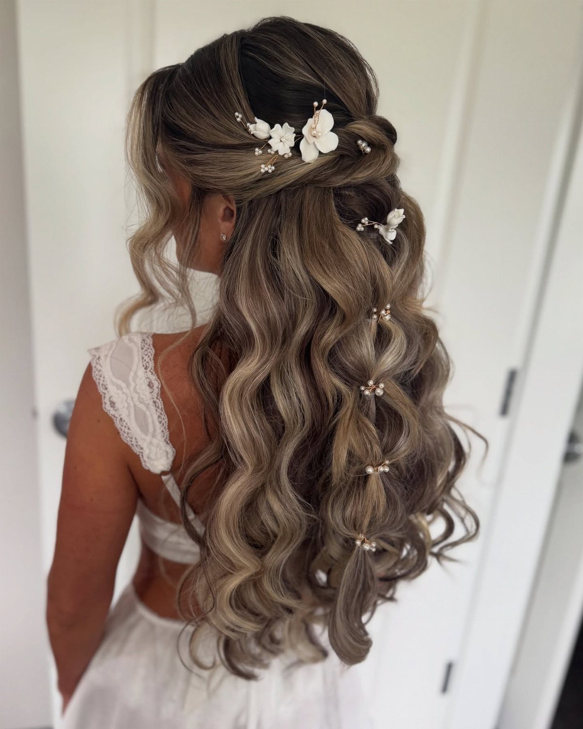 Bride wears pinned-back curls with floral clips and pearl-like hair pins