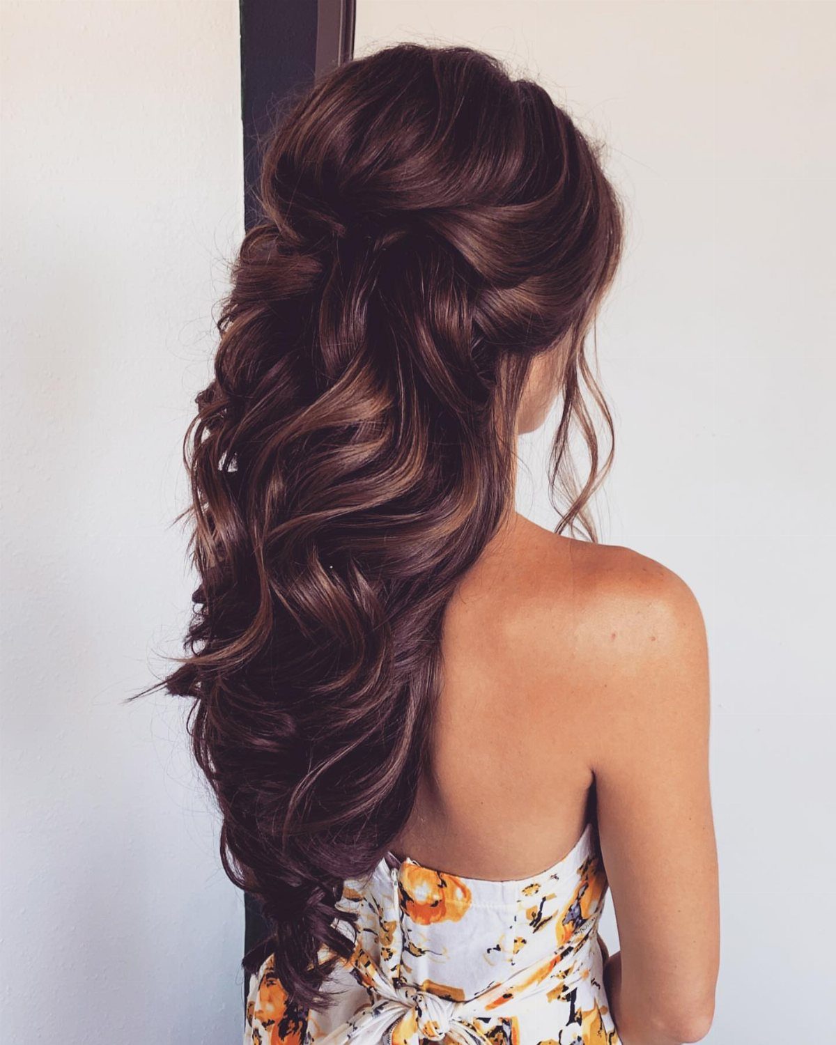 Pulled-back brunette hair cascades in voluminous curls down her back