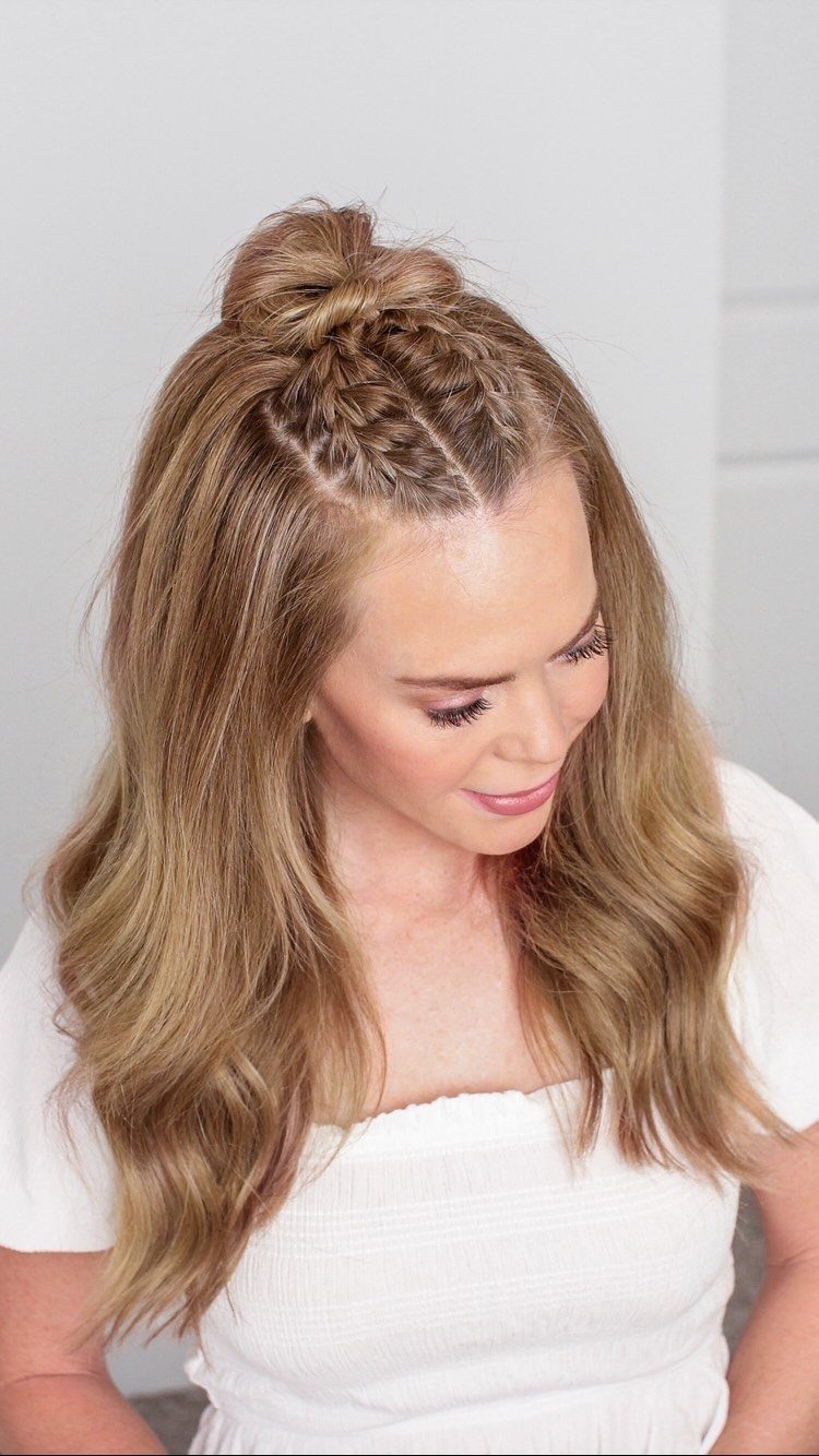 Woman wearing a crown French braid gathered into a bun with loose waves