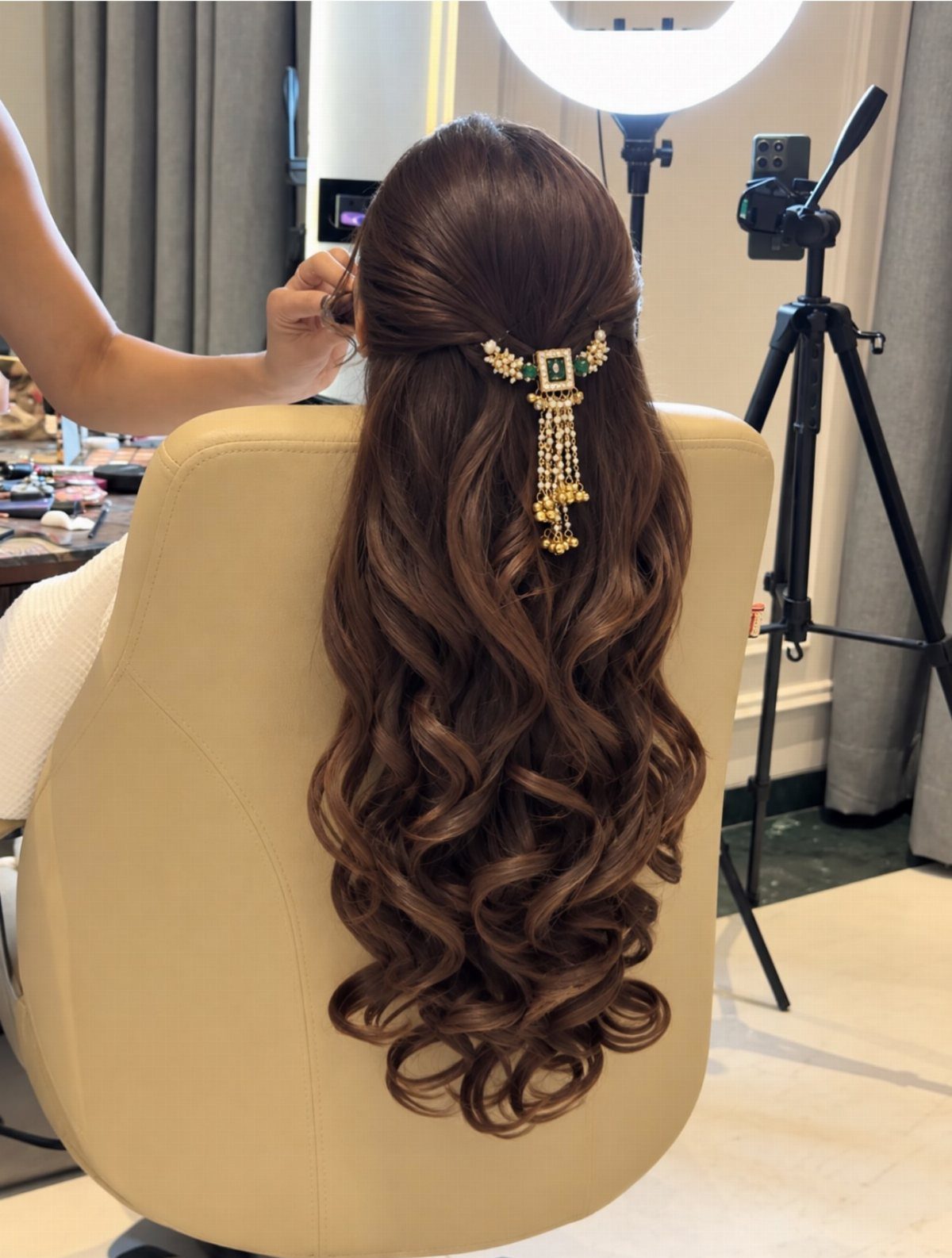 Half-up brown curls with a jeweled gold hair ornament in a salon