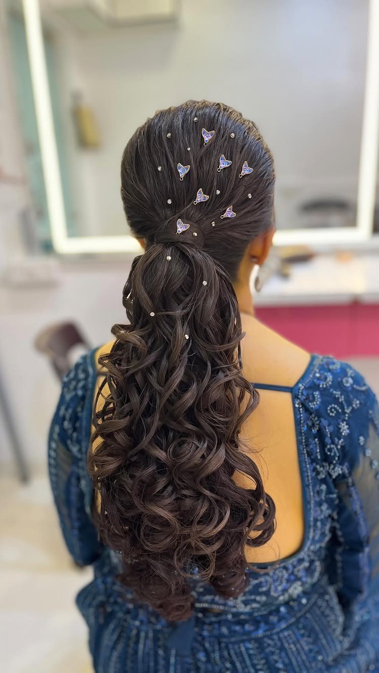Voluminous half-ponytail with long dark curls and small purple ornaments