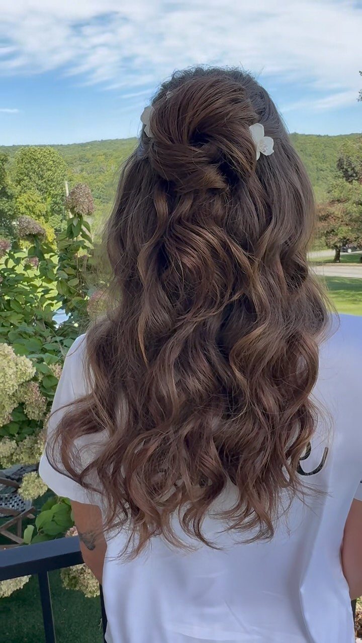 Long brown bohemian waves with a white flower pinned into a twist