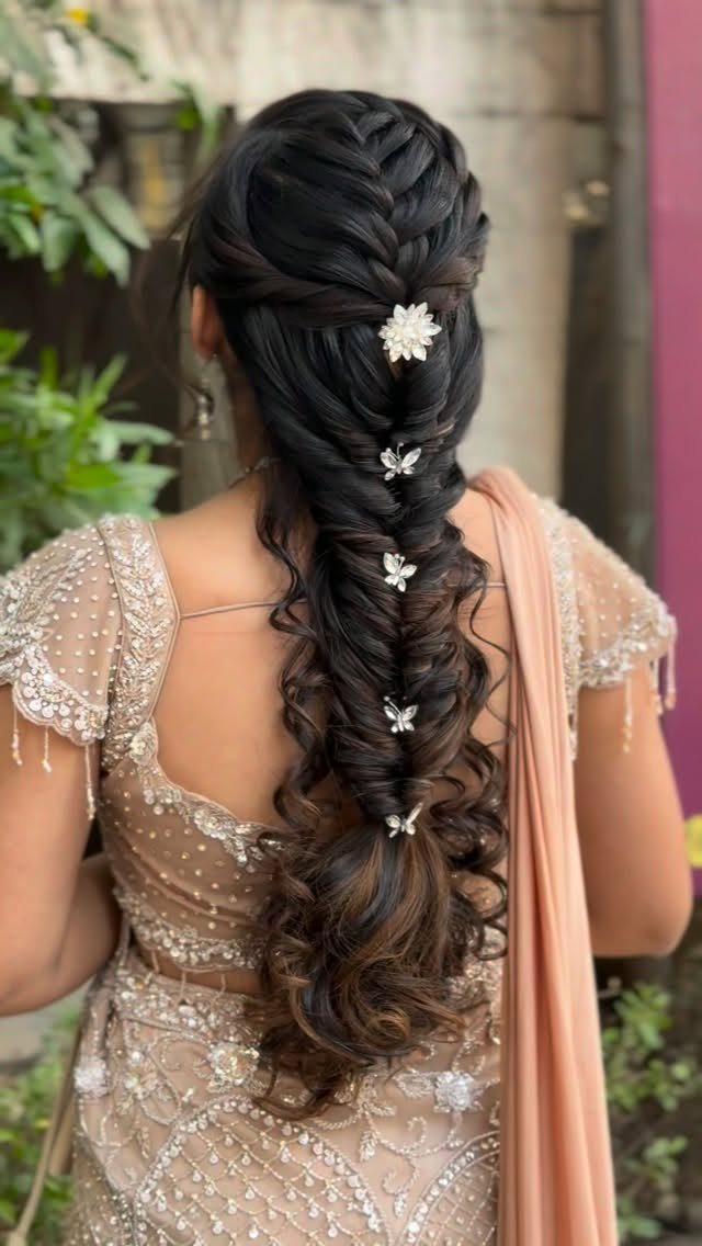 Long dark hair arranged in an intricate bridal braid with floral clips and loose curls