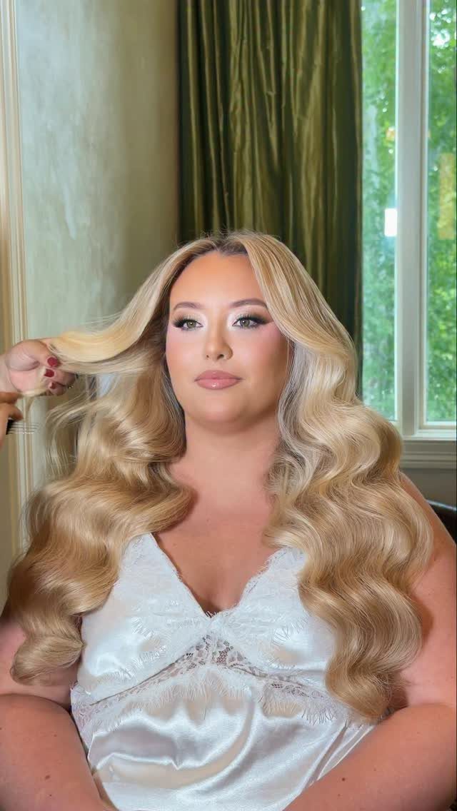 Woman with long blonde Hollywood waves wearing a white satin top