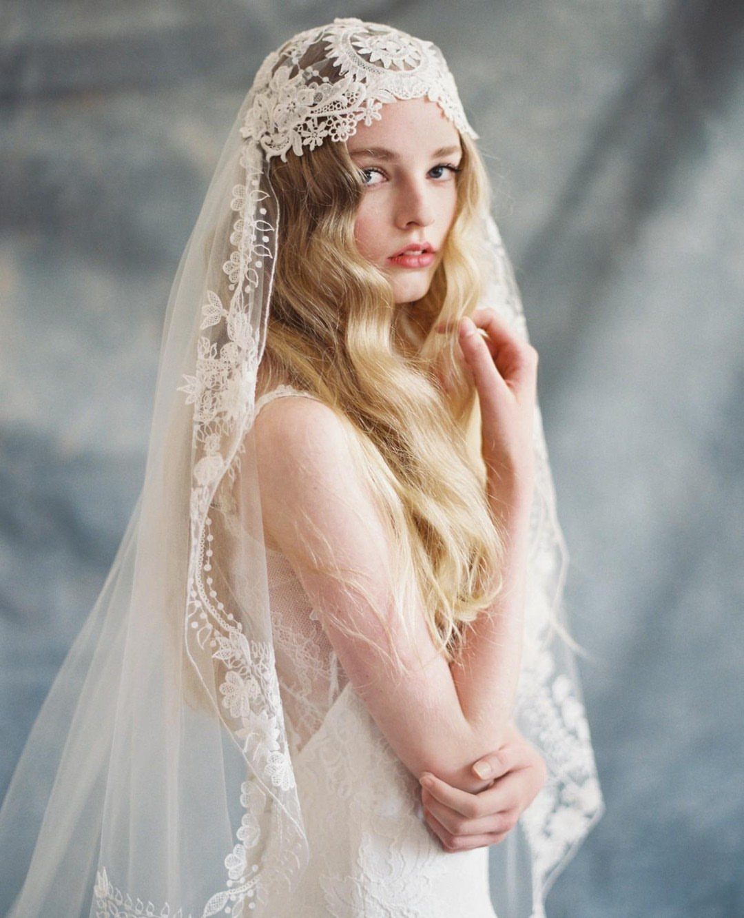 Bride wearing a vintage lace Juliet cap over long flowing blonde hair