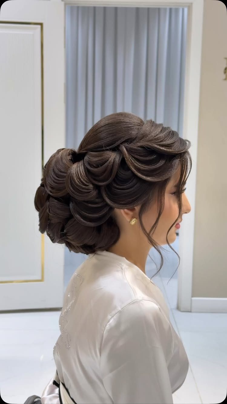 Woman with long brown hair styled in a looped bridal updo