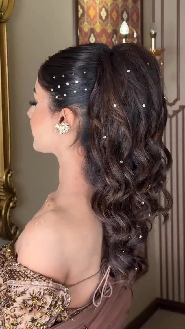 Woman with long dark hair in a curled high ponytail decorated with pearl pins