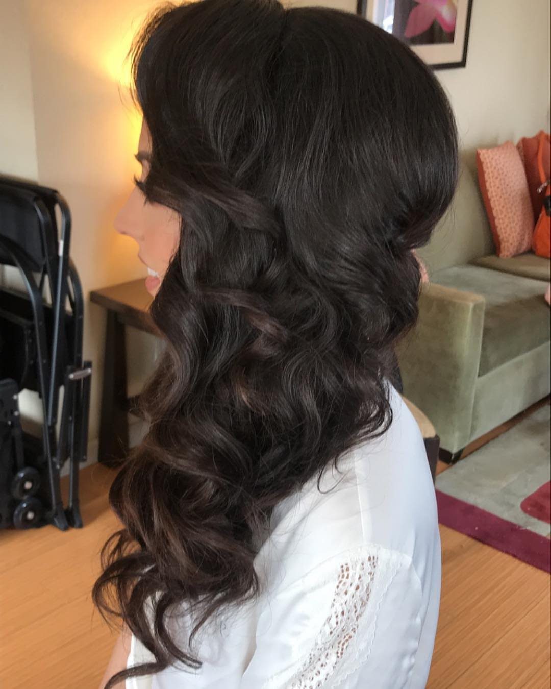 Long black curls swept over one shoulder on a person in a white top