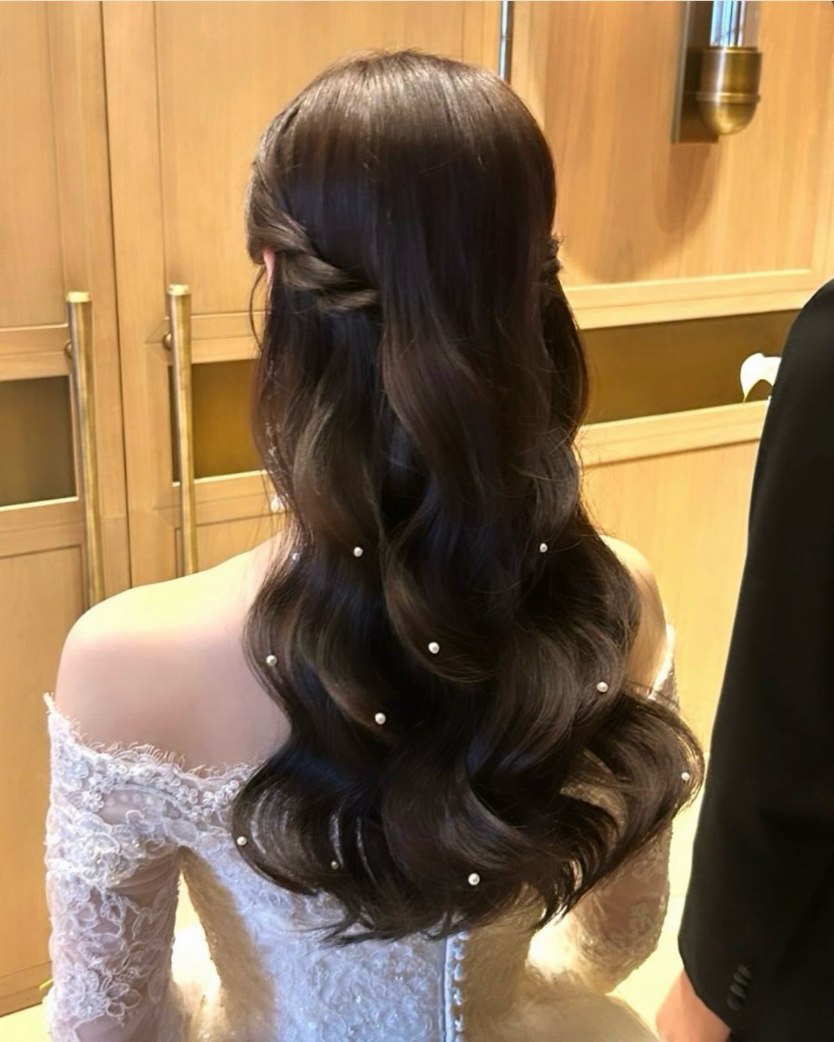 Bride's long wavy half-ponytail decorated with scattered pearl pins