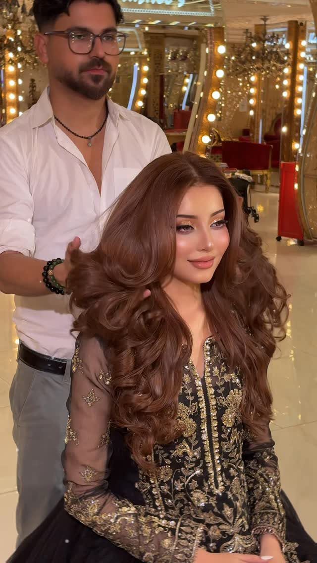 Woman with long, voluminous brown curls seated in a brightly lit salon