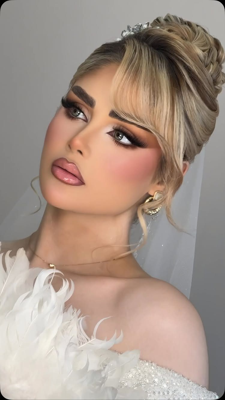 Blonde bride poses with a dimensional braided updo and loose face-framing strands