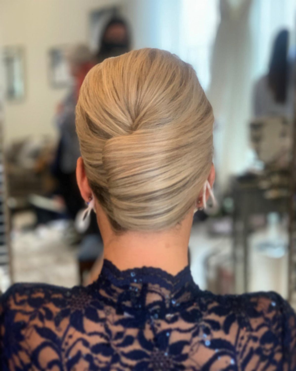 Blonde hair styled into a smooth French twist at the back of the head