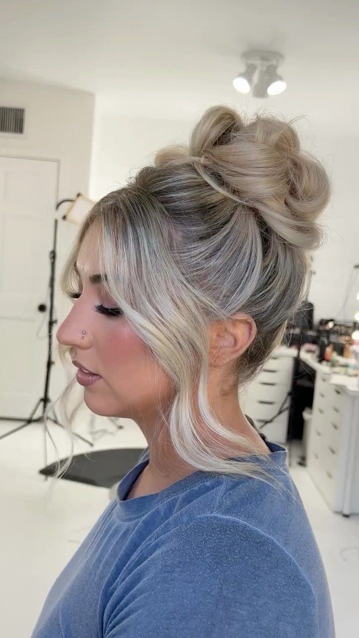 Blonde woman wearing a high loose bun with face-framing strands in a salon