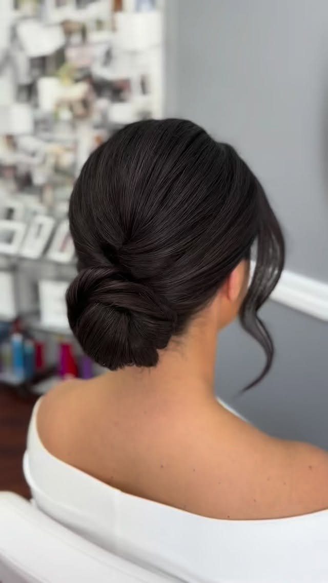 Woman wearing a smooth low bun with a loose face-framing curl