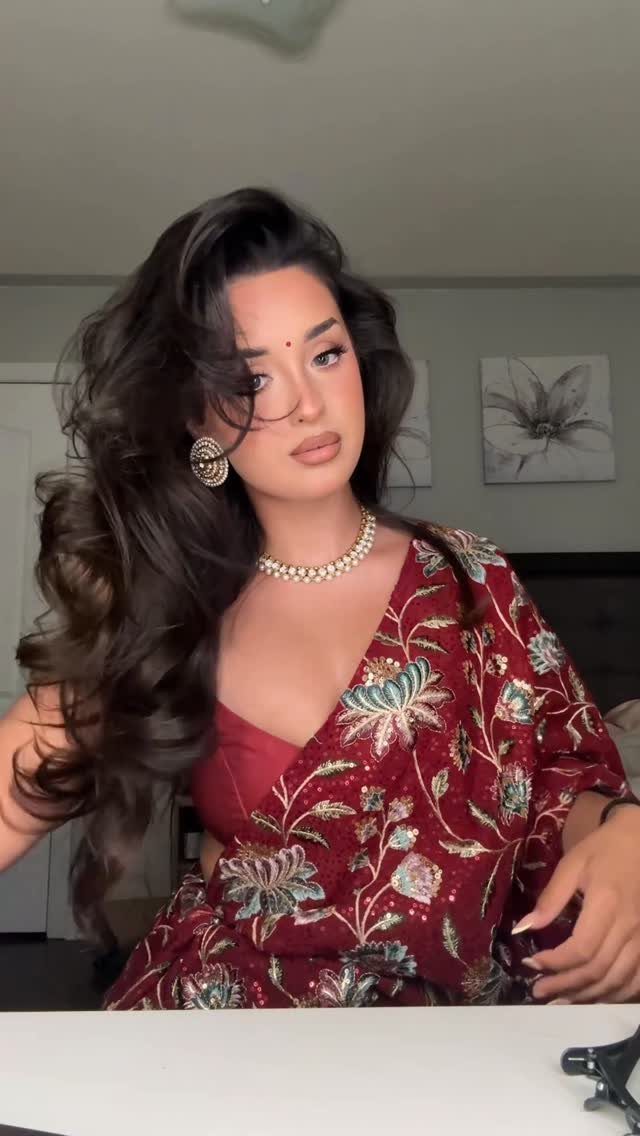 Woman with side-parted, voluminous dark hair worn loose and a red floral robe