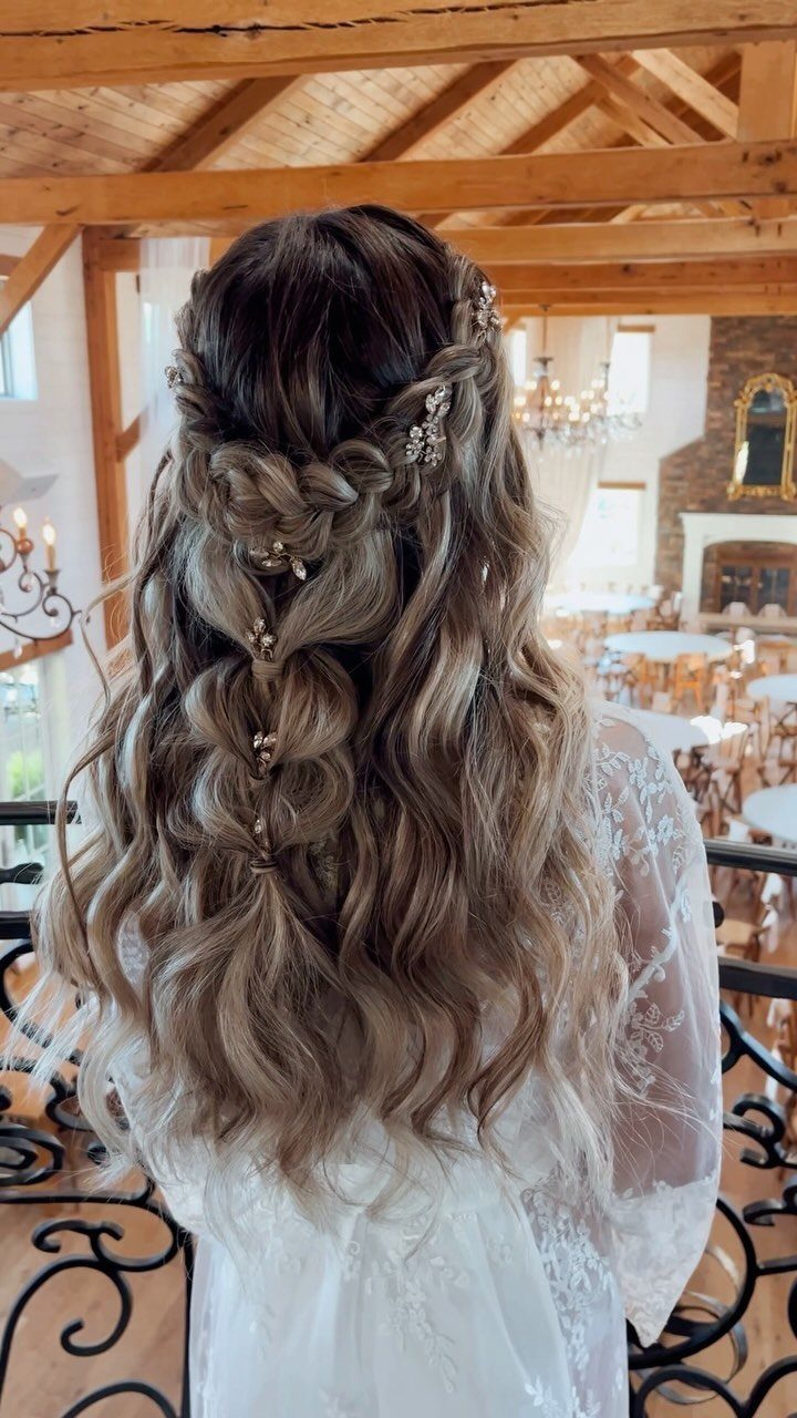 Half-up braided bridal hairstyle with jeweled pins over long, wavy brown hair