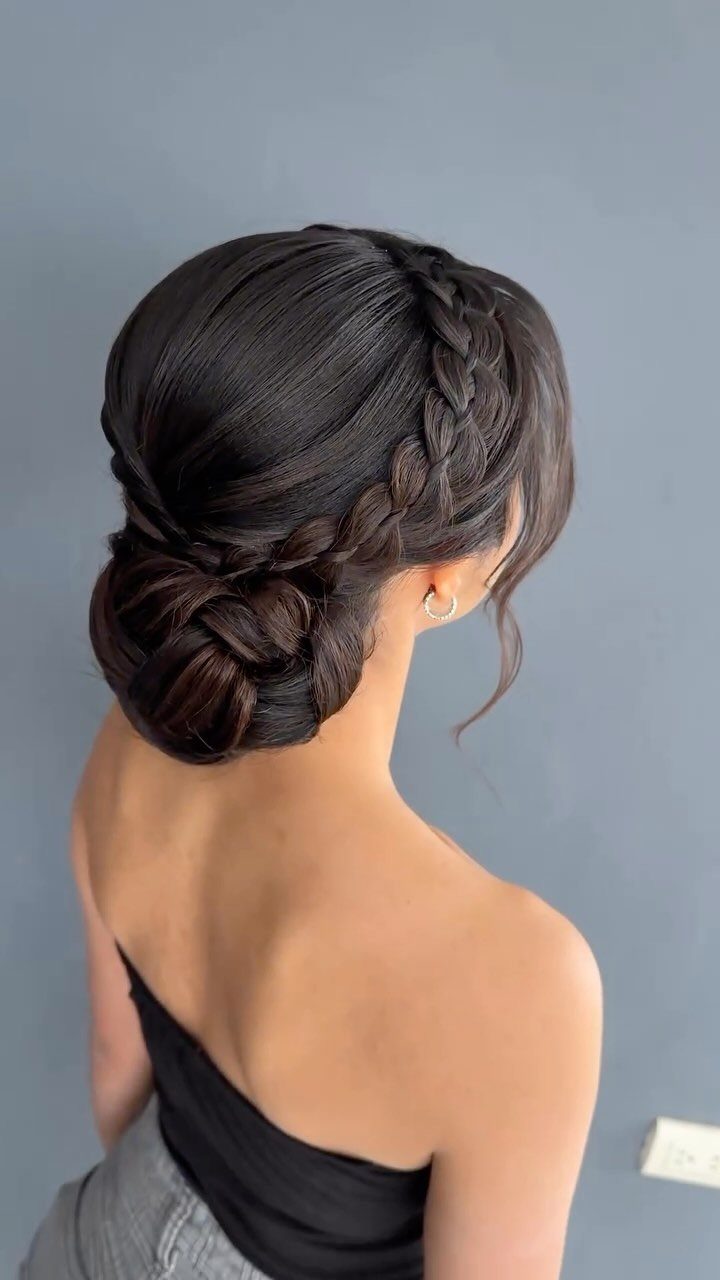 Woman displaying a dark braided updo gathered into a low bun