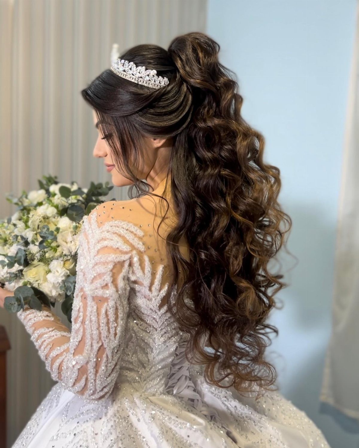 Bride wearing a high curly ponytail with a jeweled hairpiece