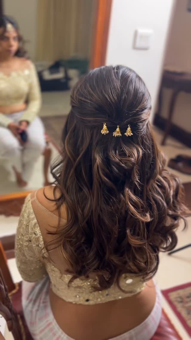 Loose dark curls fall down a woman's back beneath a small gold hair accessory