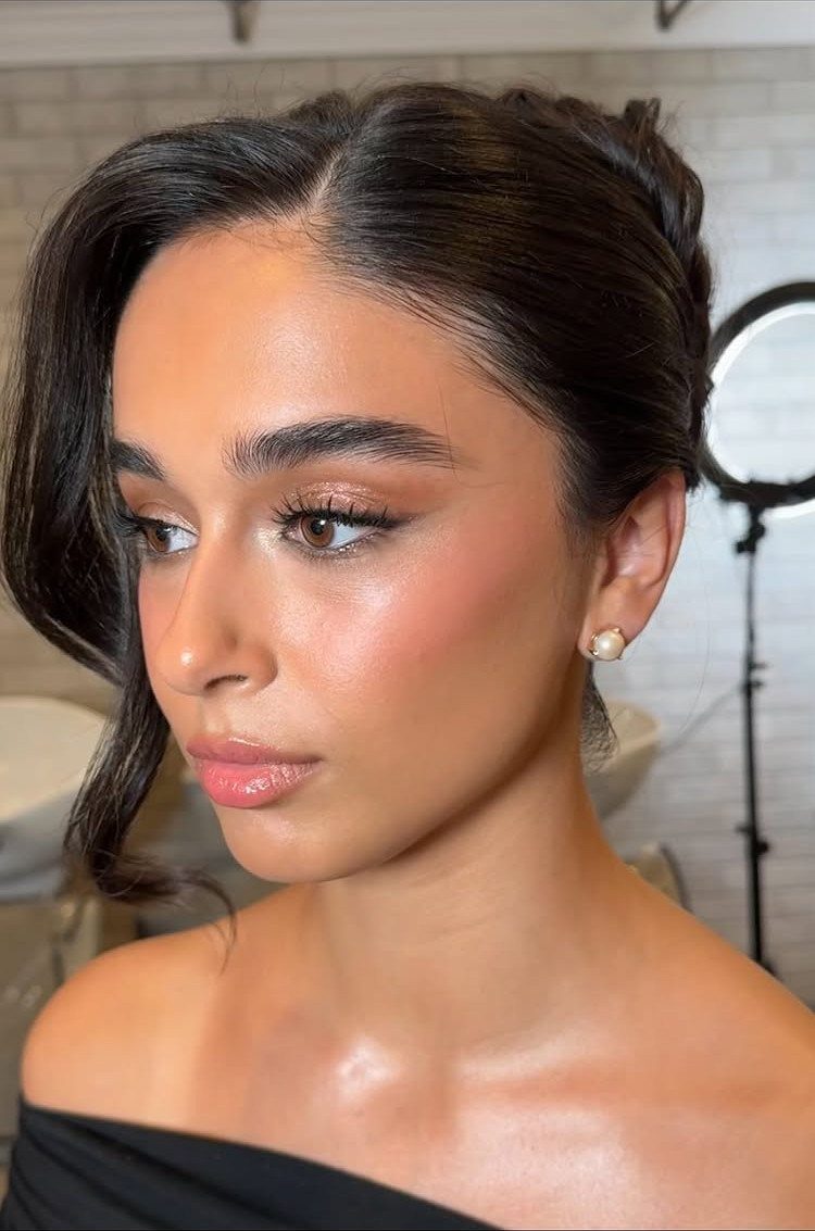 Woman with a loose dark updo and a face-framing strand
