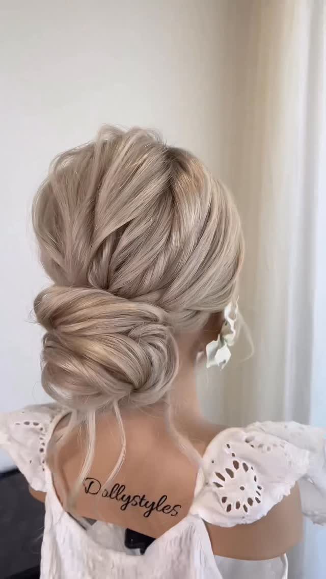 Blonde hair styled in a voluminous twisted low updo at the nape