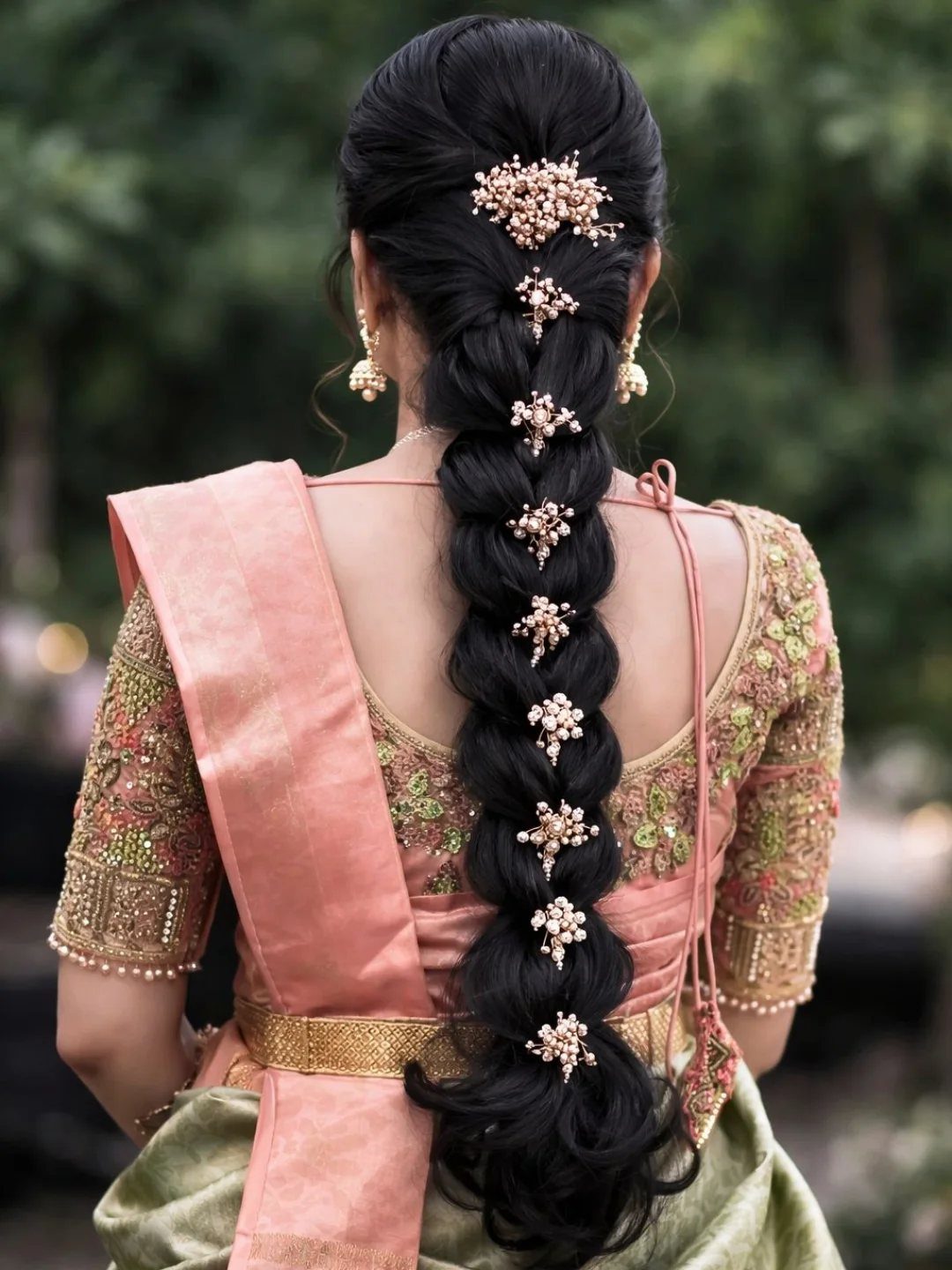 Long black cascading braid decorated with jeweled floral ornaments on a woman