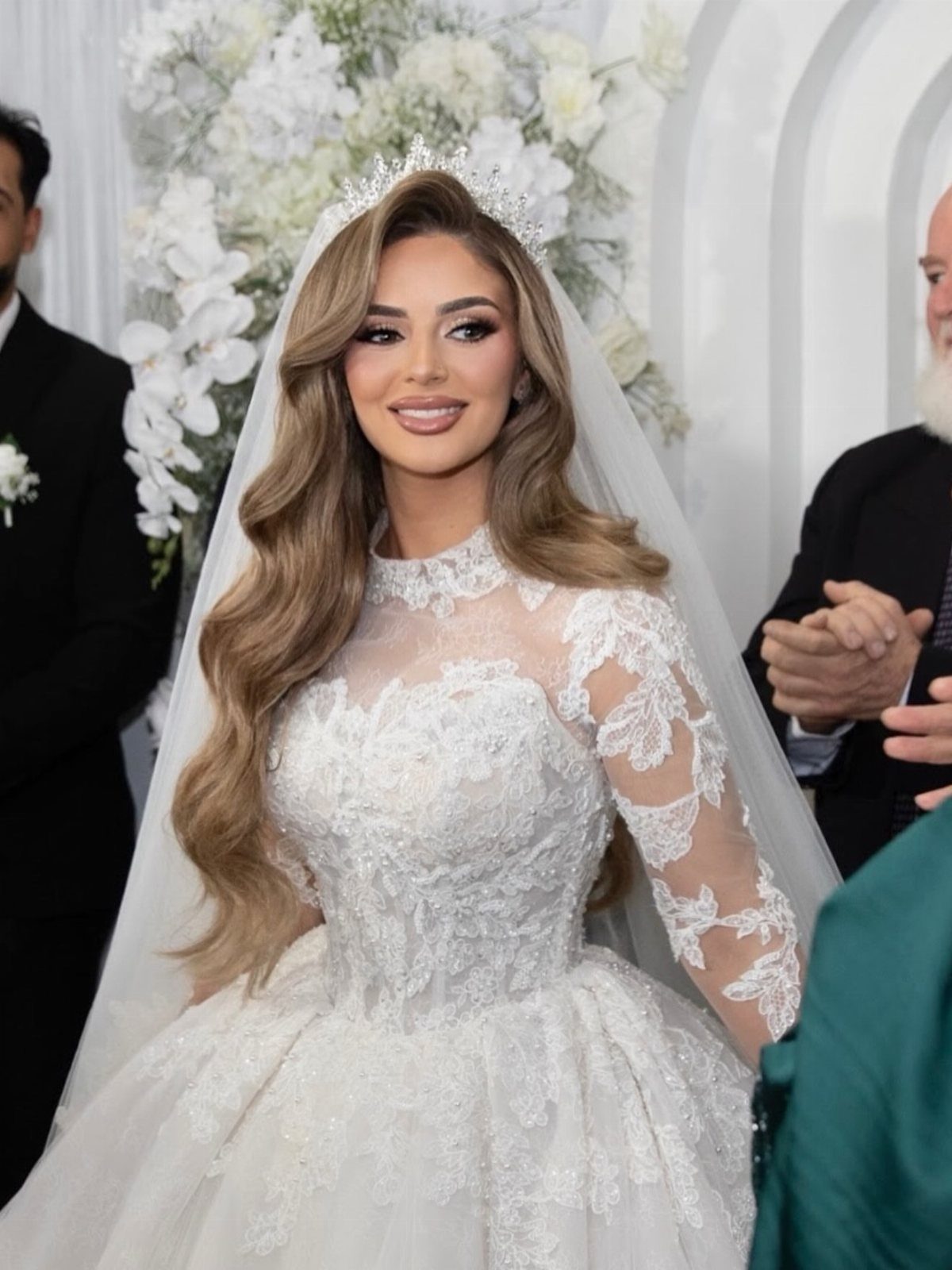 Bride with long blonde waves styled with a side part beneath her veil