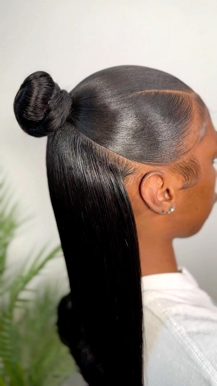 Woman wearing glossy black hair smoothed into a bun with a long straight section