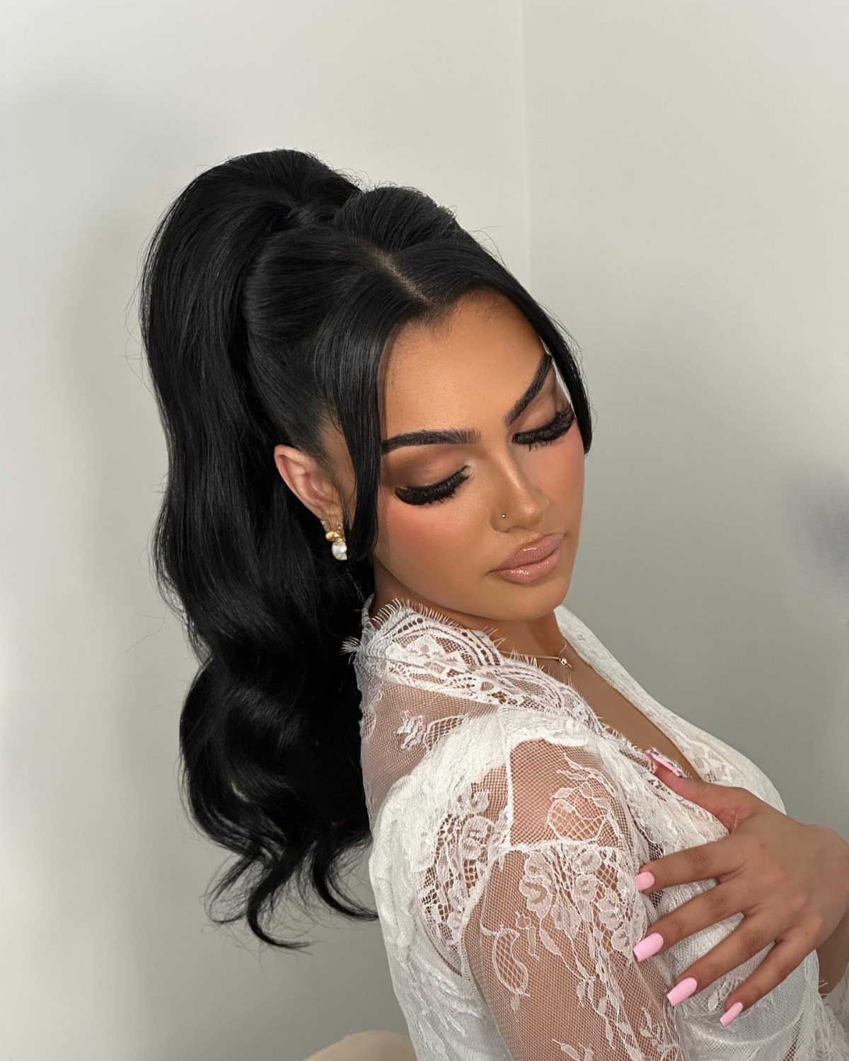 Woman poses with a polished high ponytail and curled lengths
