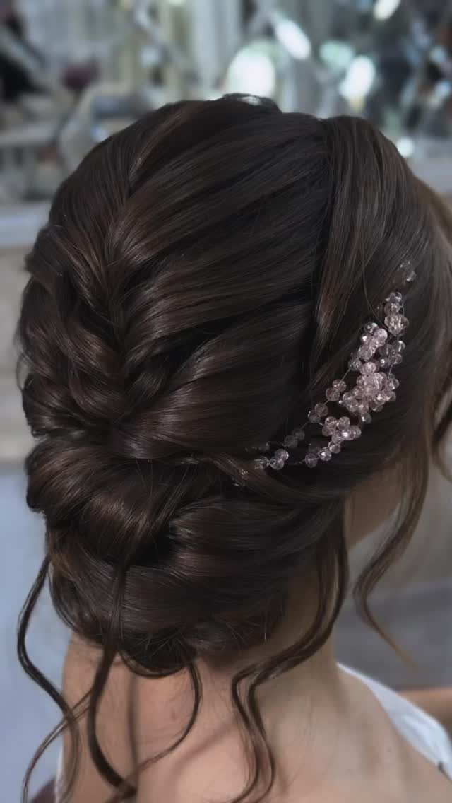 Dark textured bridal bun with jeweled hairpiece and loose face-framing curls.