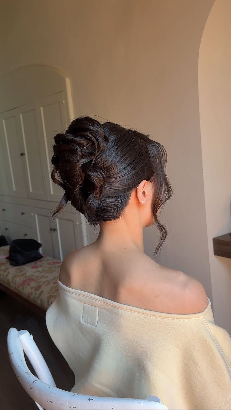 Woman showcasing a brunette bridal updo with a loose curl beside her face
