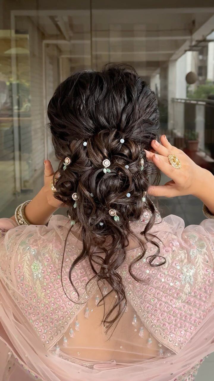 Loose dark updo with curled tendrils and floral pins, adjusted by hand